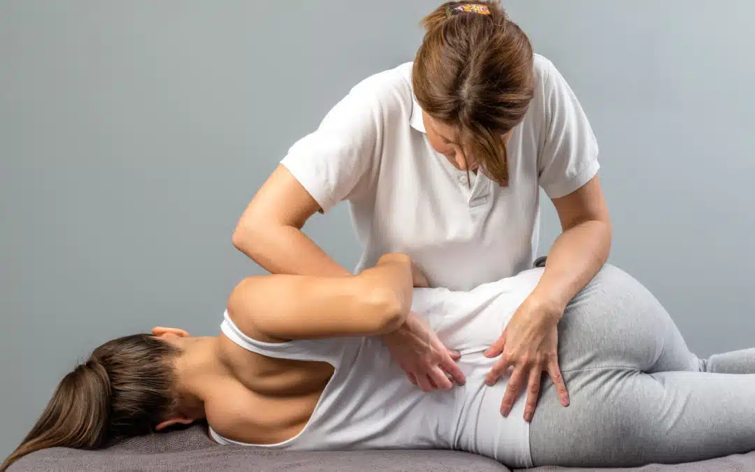 Female physiotherapist doing manipulative spine treatment on young patient.