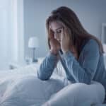 a woman in a bed experiencing a headache