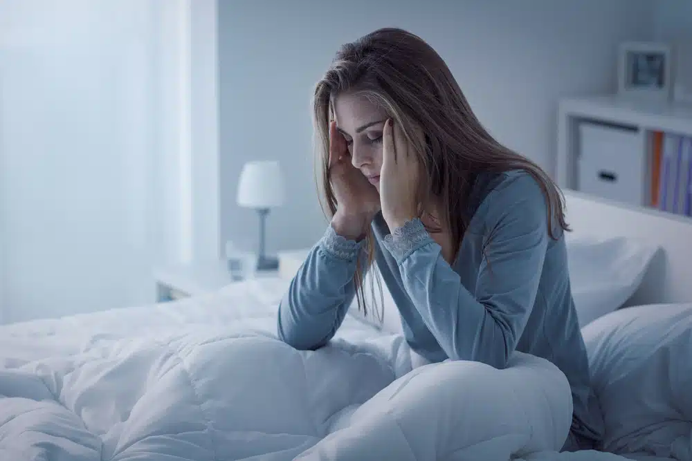 a woman in a bed experiencing a headache
